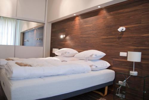 a bed with white pillows and a wooden wall at Apartman U Kolonady in Karlovy Vary