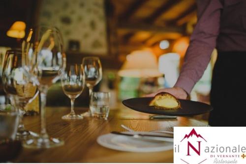 a person holding a plate of food on a table with wine glasses at Albergo Nazionale in Vernante