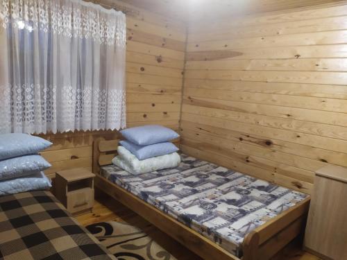 a bedroom with wooden walls and a bed with pillows at Лукі in Svityazʼ