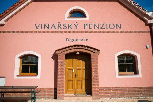 a pink building with a wooden door in front at Penzion Sudomír in Sudoměřice