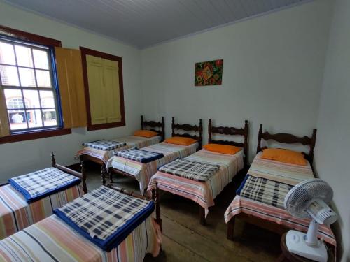 Cette chambre comprend 4 lits et une fenêtre. dans l'établissement Pousada Dona Dazinha, à Diamantina