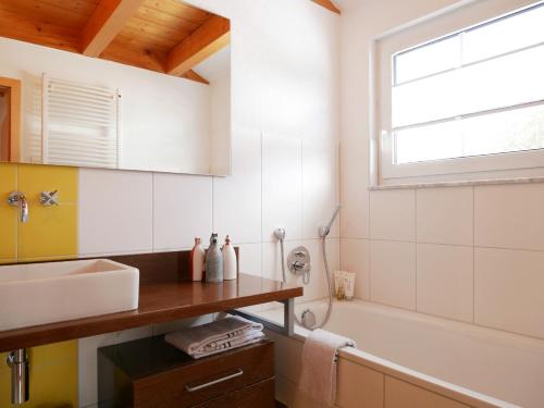 a bathroom with a sink and a tub and a window at Oskar's Chalets in Hinterzarten