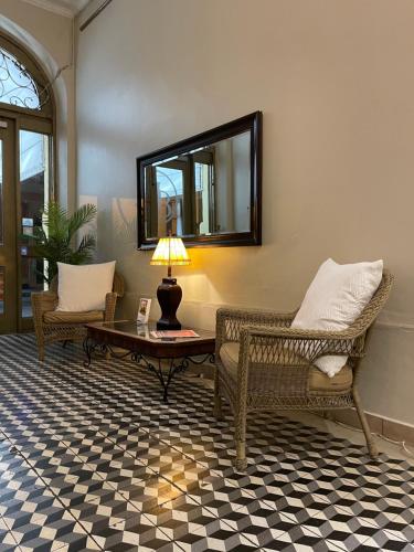 a living room with two chairs and a table and a mirror at Boutique Hotel Belgica in Ponce