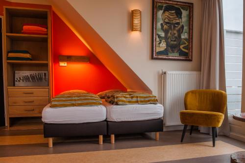 a bedroom with a bed with an orange wall at Studio aan Zee in Westkapelle