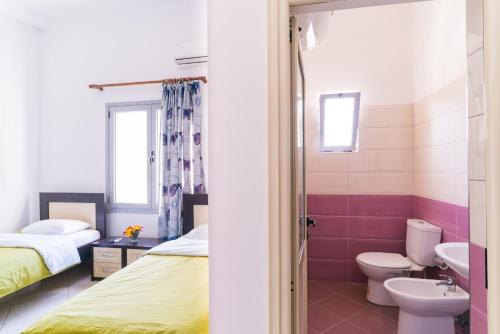 a bathroom with two beds and a toilet and a sink at Hotel Shpetimi in Çorovodë