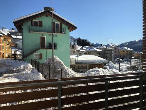 a green building with a balcony in a snowy city at Residence Aurora in Lavarone