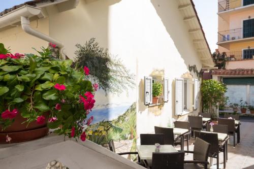 a patio with tables and chairs and a potted plant at Bella Vista Beach Hotel in Benitses