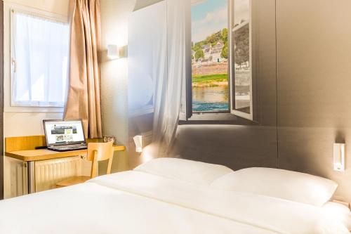 a hotel room with two beds and a desk with a laptop at B&B HOTEL TOURS Sud Joué-lès-Tours in Joue-les-Tours