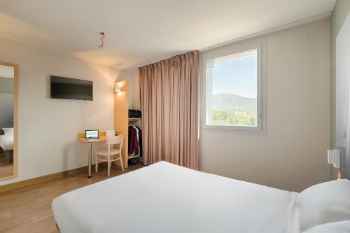 a hotel room with a bed and a window at B&B HOTEL Marseille Aéroport Saint-Victoret in Saint-Victoret