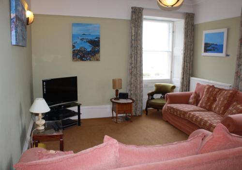 a living room with a pink couch and a tv at Guillemots in North Berwick