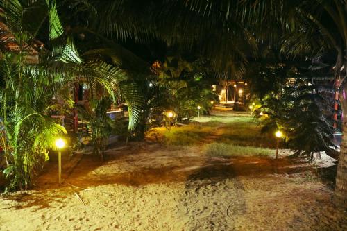 a resort yard at night with palm trees and lights at Secret Garden Arambol in Arambol