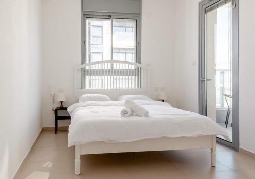 a white bedroom with a bed with a towel on it at Oַ&O Group- Luxury 3BR APT 33 Floor Sea View Tower in Bat Yam