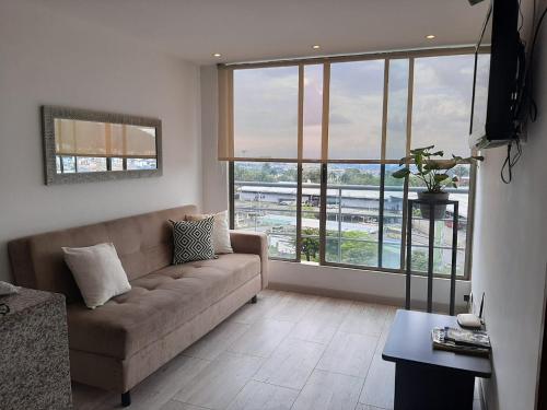 Santorini Apartamentos Amoblados في بيريرا: غرفة معيشة مع أريكة ونافذة كبيرة