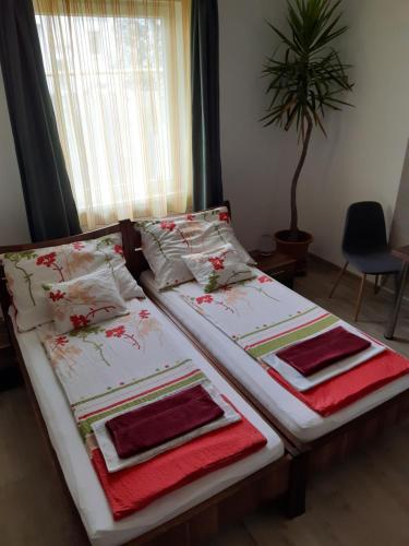 Duas camas com toalhas e almofadas num quarto em M47 Vendégház-Airport em Debrecen