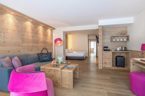 a living room with a blue couch and pink chairs at POP-UP LIVING Zell am See in Zell am See