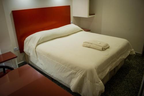 a bed with a white blanket and a red headboard at WISZ-V in Belén