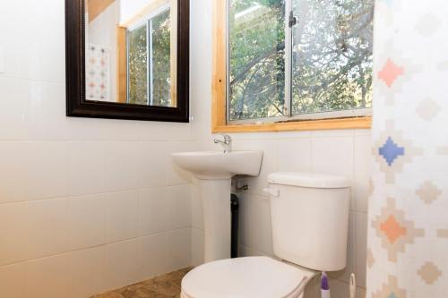 uma casa de banho com um WC, um lavatório e uma janela em Parcela Paso del León (Cabañas) em Olmué