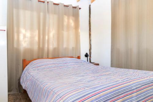 a bedroom with a bed with a striped blanket at Parcela Paso del León (Cabañas) in Olmué
