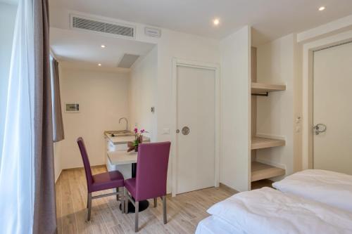 Storo的住宿－Barambana Rooms，一间卧室配有一张桌子和一张带紫色椅子的床。