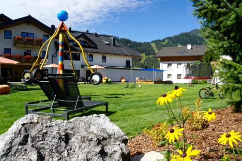 a playground in a yard with a rock and flowers at Apart-Hotel Alpinsonnenresidenz in Fiss