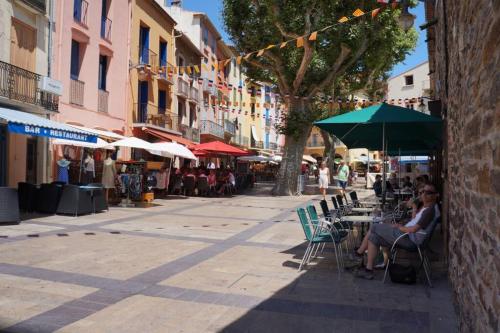 two people sitting under an umbrella on a city street at Collioure Centre Ville, Calme, Clim in Collioure
