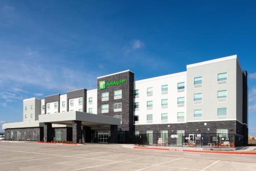 a large white building with a green sign on it at Holiday Inn Fort Worth - Alliance by IHG in Fort Worth