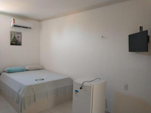 a small bedroom with a bed and a small refrigerator at Pousada beira rio in Baía da Traição