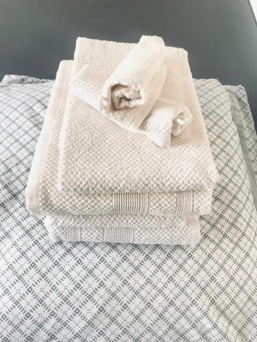- une pile de serviettes assises au-dessus d'un lit dans l'établissement Charmant 4 pièces à 100 m de la plage, à Nice