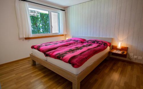 a bedroom with a bed with pink sheets and a window at Ferienwohnung Selinda in Niederried