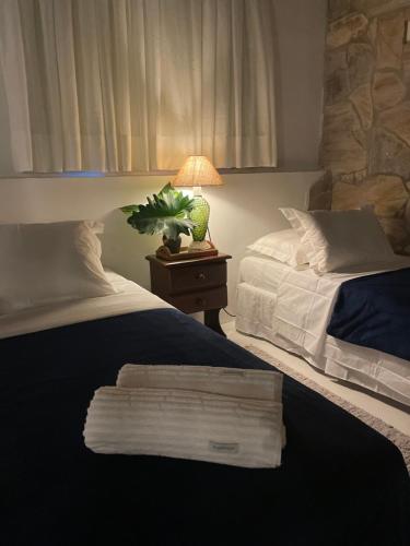 a bedroom with two beds and a table with a lamp at Kûara Pipa in Pipa