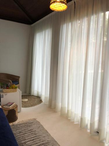 a living room with white curtains and a chandelier at Kûara Pipa in Pipa