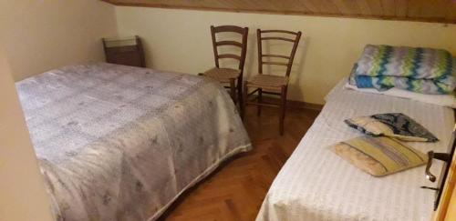 1 dormitorio con 2 camas y 2 sillas en La mansarda sul fiume, en Abetone