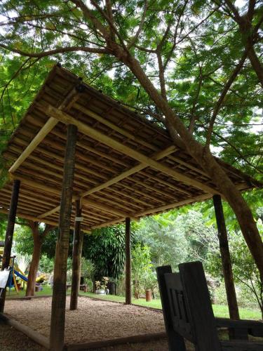 a wooden pavilion with a bench under a tree at Hotel Santiago in Lindóia