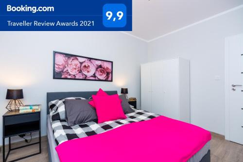 a bedroom with a pink bed with a black and white at Apartment Antonio in Gdańsk