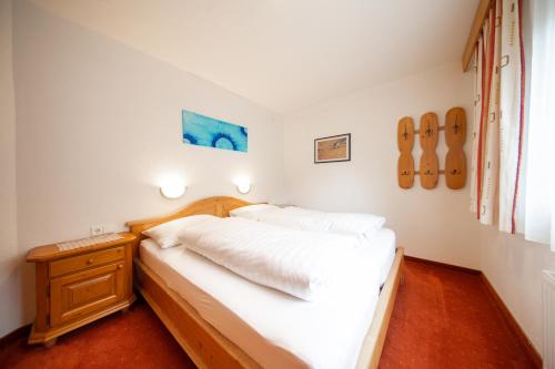 1 dormitorio con 1 cama con sábanas blancas y mesita de noche en Haus Veronika, en Sölden