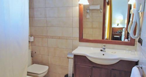 a bathroom with a sink and a toilet and a mirror at Hotel La Masia in L'Estartit