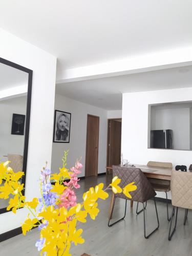 ein Wohnzimmer mit einem Tisch, Stühlen und Blumen in der Unterkunft 3 Apartamento completo Cedritos Minimalista in Bogotá