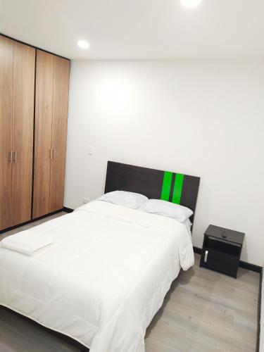 a bedroom with a large white bed with a green accent at 3 Apartamento completo Cedritos Minimalista in Bogotá
