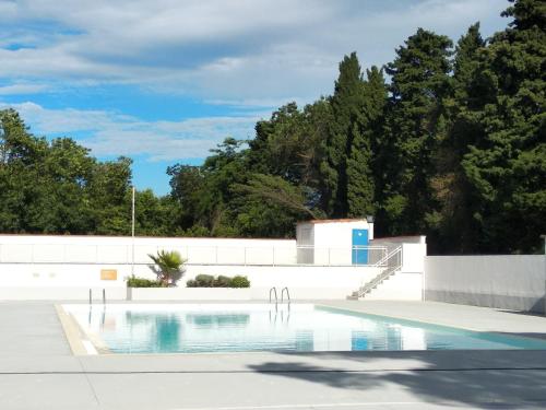 ein Schwimmbad in einem Park mit Bäumen im Hintergrund in der Unterkunft Camping Parc des 7 Fonts in Agde