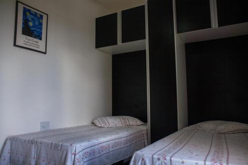 2 camas en una habitación con paredes blancas y negras en Amsterdam lofts 2 en Poços de Caldas