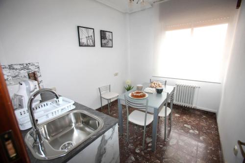a kitchen with a sink and a table with chairs at Pensión Como en Casa in Rincón de Soto