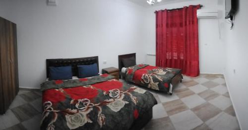 een slaapkamer met 2 bedden en een rood gordijn bij Aramca in Bab Ezzouar