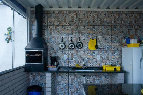a kitchen with a stove and a wall with tiles at Amsterdam lofts 1 in Poços de Caldas