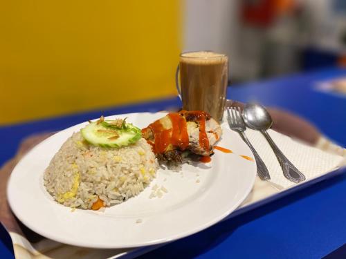 a plate of food with rice and a drink on a table at Hotel Aman- Nilai & KLIA in Nilai