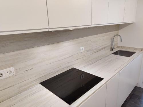 a kitchen counter with a sink and white cabinets at Casa Bianca in Cala Vadella