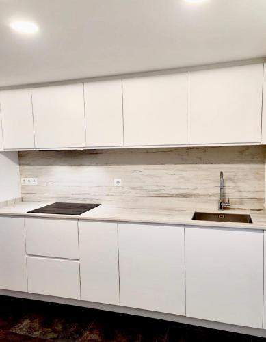 a white kitchen with white cabinets and a sink at Casa Bianca in Cala Vadella