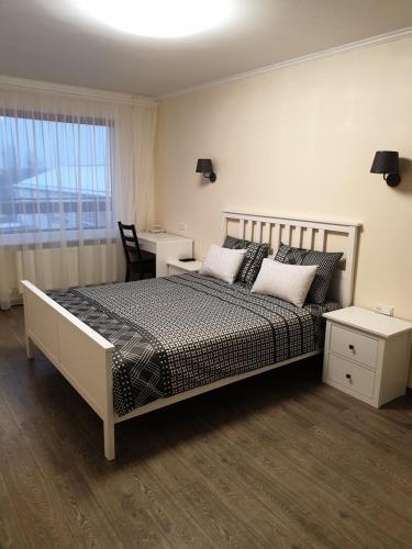 a bedroom with a bed and a desk and a window at Swan City Apartment in Gulbene