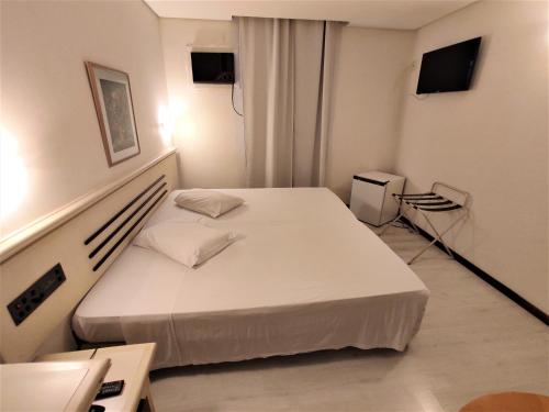 a bedroom with a white bed in a room at Granville Hotel in Curitiba