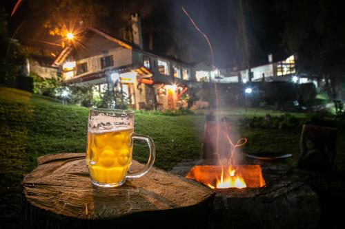 uma caneca de cerveja sentada numa mesa ao lado de uma fogueira em Pousada Aguia da Montanha em Monte Verde