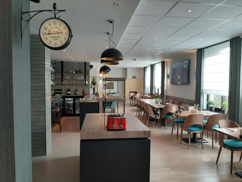 een restaurant met tafels en stoelen en een klok aan de muur bij Hotel Limburgia in Kanne